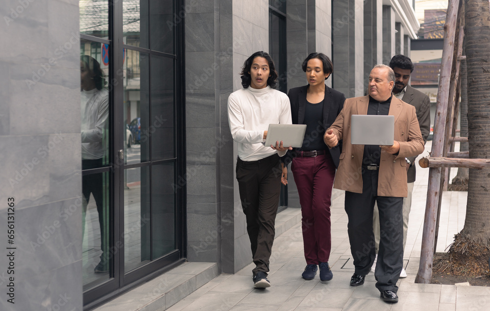Fototapeta premium Business team meeting. A group of diversity businessman people colleagues talking while walking against contemporary corporate buildings in the city.