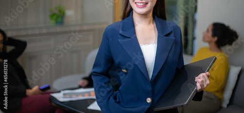 Successful and attractive young Asian businesswoman holding laptop in the modern office workplace. Happy young adult female smiling.