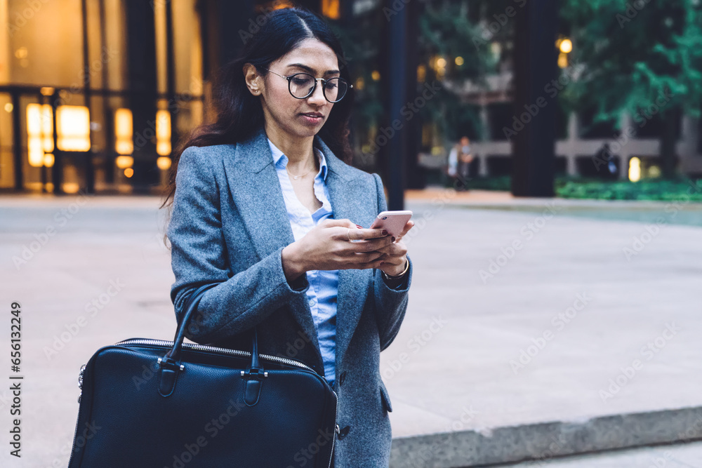 Obraz premium Ethnic female going down stairs with smartphone