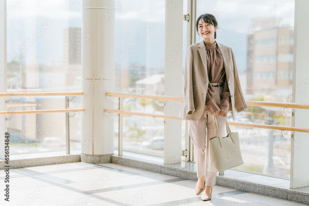 Obraz premium ビル・駅・商業施設の中で待ち合わせするビジネスウーマン（全身・ファッション） 