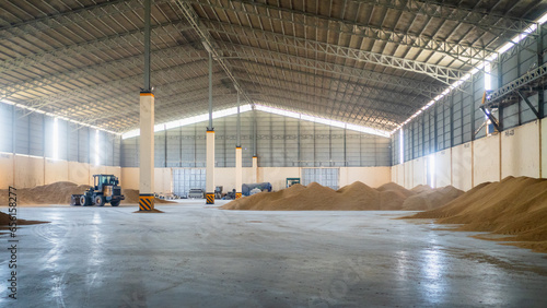 Bulldozer pushing pile of dried paddy rice inside a huge bulk storage warehouse. Rice mill plant. photo