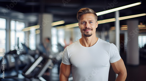 Portrait muscular fitness instructor in the gym, fitness trainer wearing sportswear standing in the background of sport gym