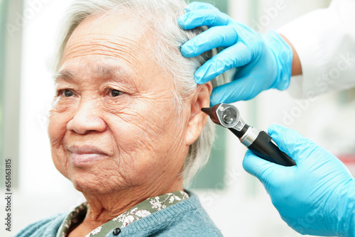 Otolaryngologist or ENT physician doctor examining senior patient ear with otoscope, hearing loss problem.