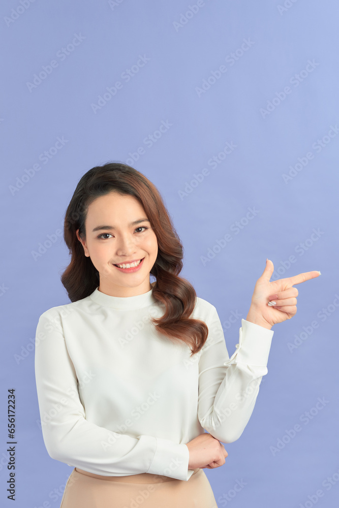 Asian young woman standing makes gesture fingers point upwards above presenting product something Asian young woman standing makes gesture fingers point upwards above presenting product something
