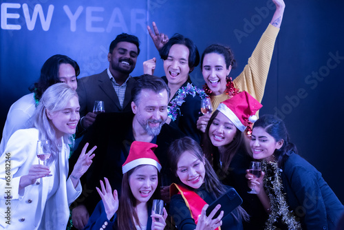 A group of female and male friends of various backgrounds take a selfie during a New Year's party.