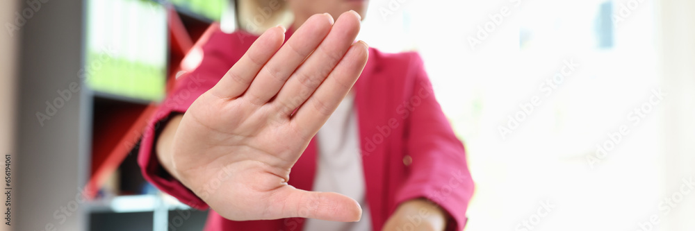 Woman shows refusal gesture sitting at table in office Woman shows refusal gesture sitting at table in office