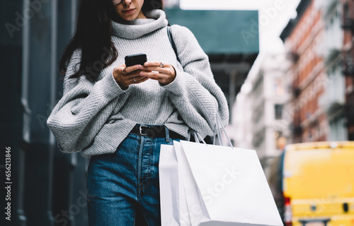 Trendy young woman browsing on mobile at street