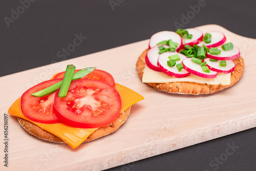 Different Cracker Sandwiches with Tomato, Cucumber, Radish and Cheese on Cutting Board. Easy Breakfast. Diet Food. Quick and Healthy Sandwiches. Crispbread with Tasty Filling. Healthy Dietary Snack