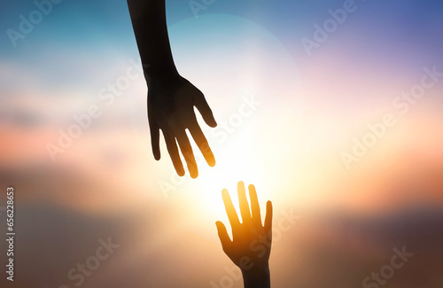 Картината върху платно Silhouette of giving a helping hand over sunset background.