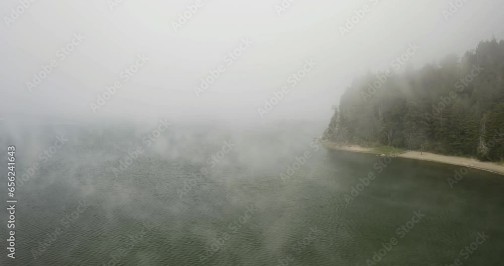 Aerial view over misty water, passing the lakeshore and a beach at a lake, in USA Aerial view over misty water, passing the lakeshore and a beach at a lake, in USA