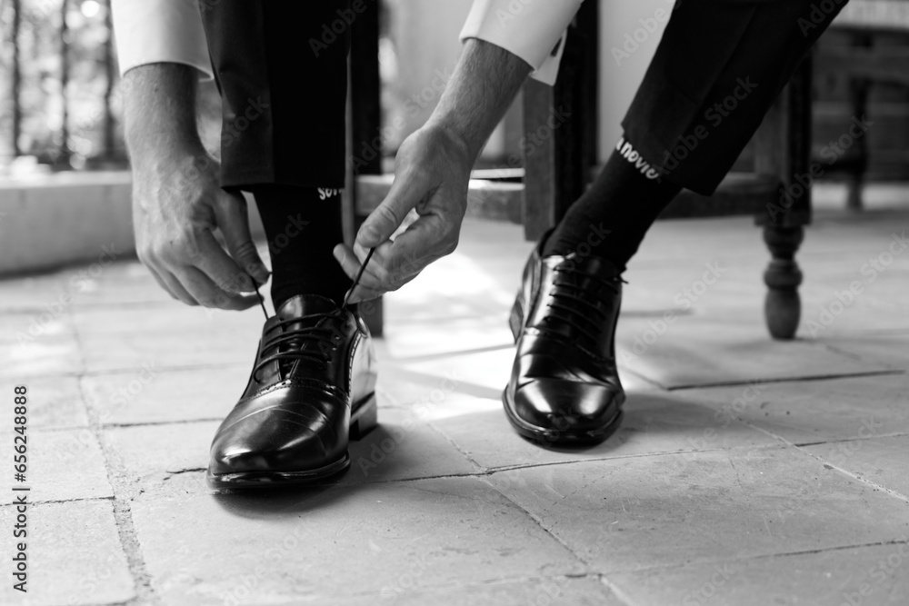 Novio poniendose los zapatos y atandose los antes de la boda Novio poniendose los zapatos y atandose los antes de la boda