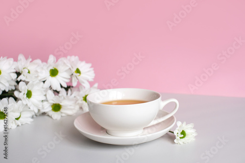 Wallpaper Mural A white cup with tea and a saucer stands on a table with white chamomile flowers Torontodigital.ca