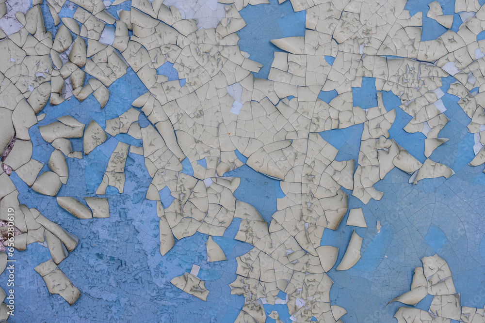 Naklejka premium Peeling paint on the wall. Old concrete wall with cracked flaking paint. Weathered rough painted surface with patterns of cracks and peeling. Grunge texture for background and design. High resolution.
