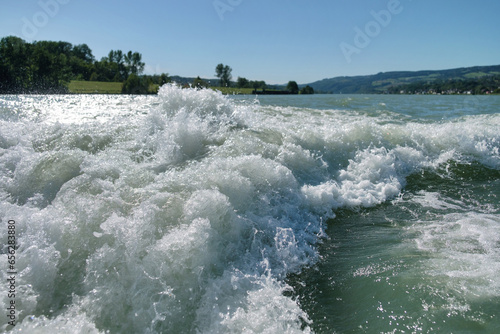 White motorboat tracks on the waves with a blurred green hills on the horizon