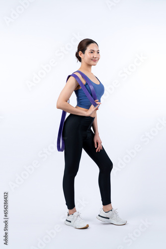 Vigorous energetic woman in sportswear portrait stretching resistance sport band. Young athletic asian woman strength and endurance training session workout routine concept on isolated background. © Summit Art Creations
