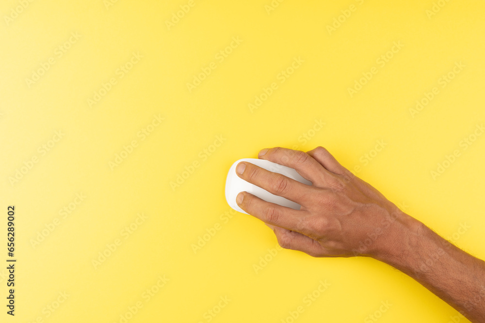 black male hand with white computer wireless mouse on isolated yellow - obrazy, fototapety, plakaty 