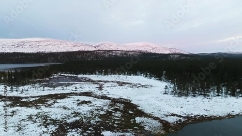 Aerial view over a snowy swamp with sunlit tunturi background, fall in Lapland photo