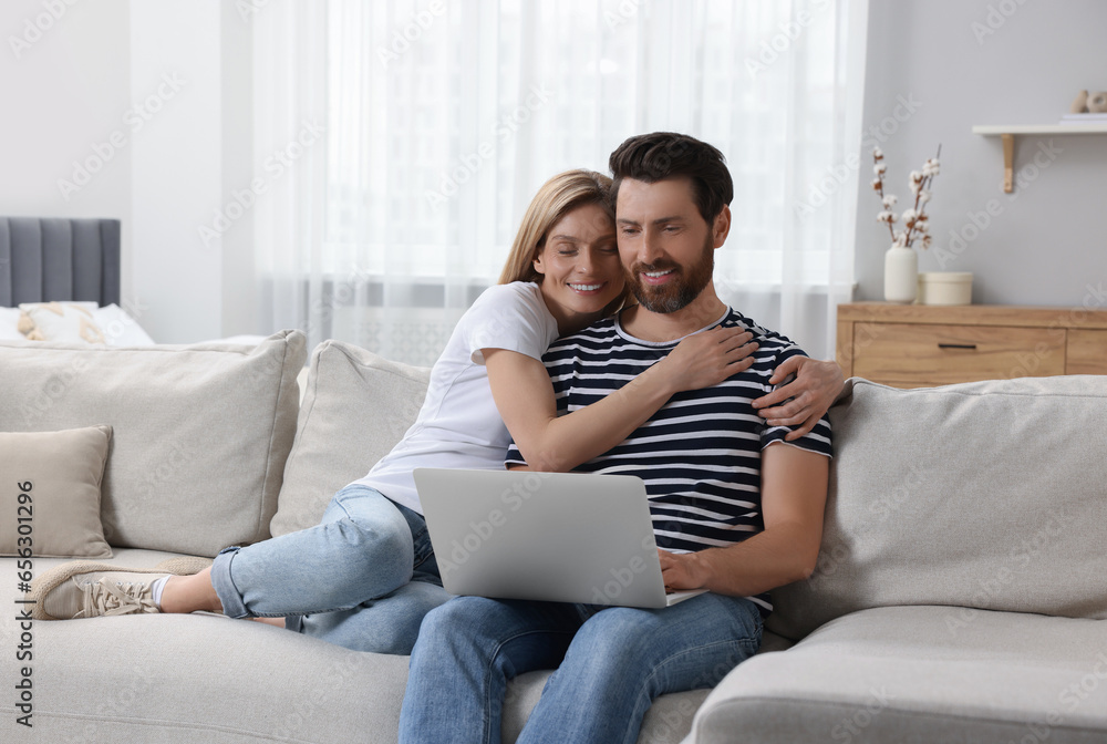 Obraz premium Happy couple with laptop on sofa at home