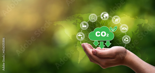 CO2 emission reduction concept, Environmental icons, global warming and renewable energy in hand on green blurred background.