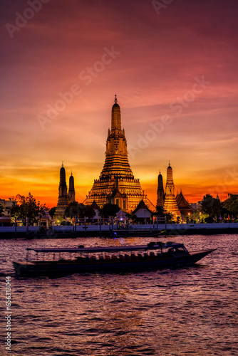 Obraz na płótnie The famous Buddhist Temple Wat Arun during dusk with boat traffic on the Chao Phraya Rriver, Bangkok, Thailand w salonie