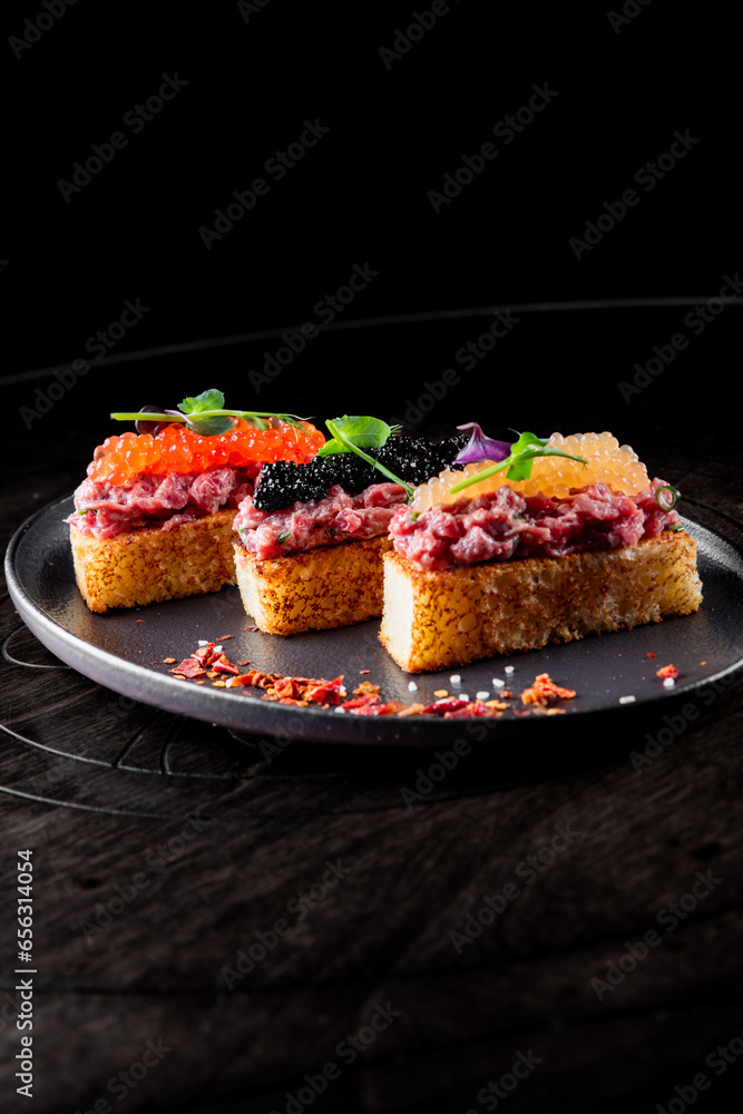 Canape with brioche, Raw beef meat tartar, salmon red caviar.