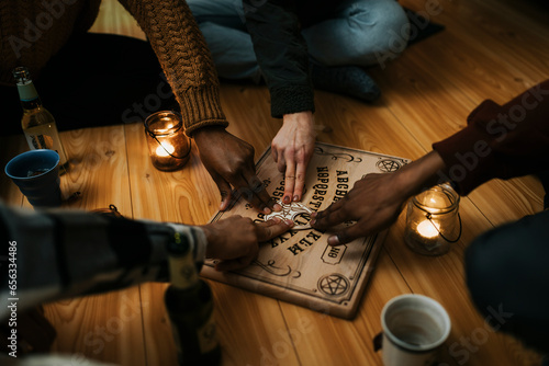 Multiracial male and female friends using ouija board in house photo