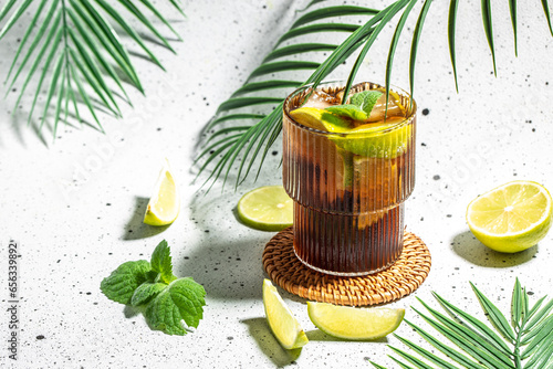 Quadro em tela Alcohol cocktail cuba libre with rum, cola, mint and lime in the glass a light b