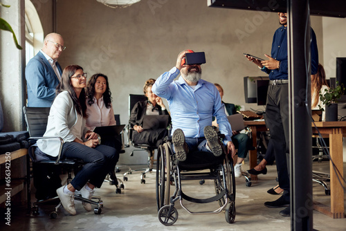 Businessman with disability wearing VR simulator amidst colleagues at creative office photo