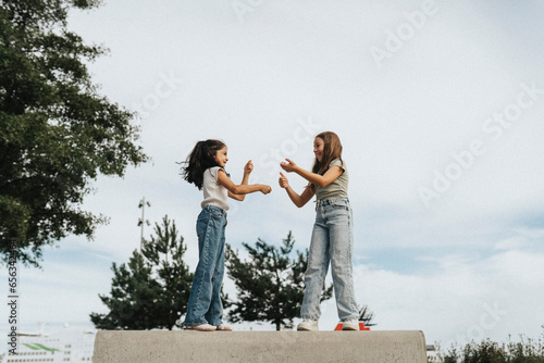 Low angle view of siblings playing while doing hand signs against sky photo