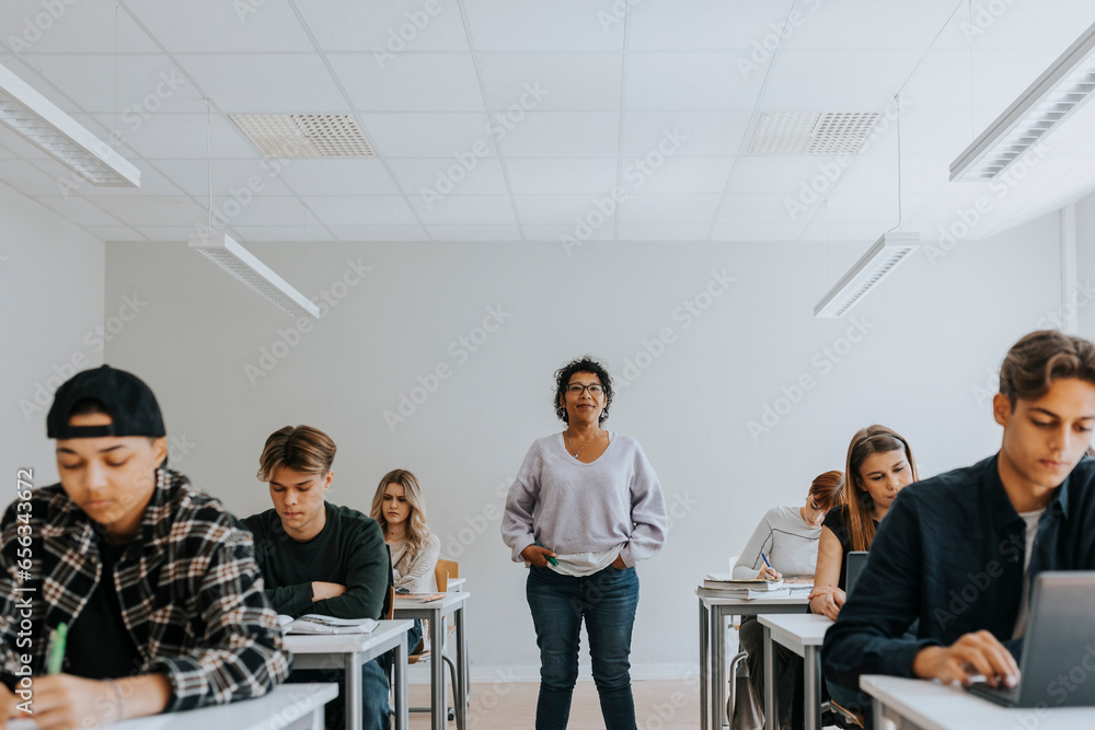 Portrait of female teacher with hands in pockets standing amidst students Portrait of female teacher with hands in pockets standing amidst students