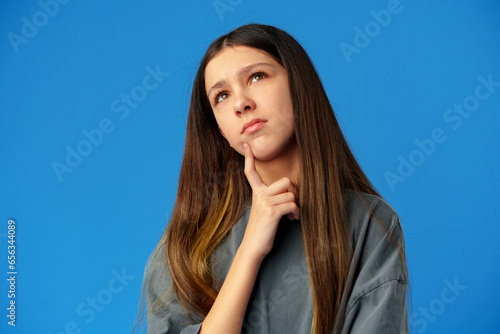 Young teen girl thinking about something over blue background © fotofabrika