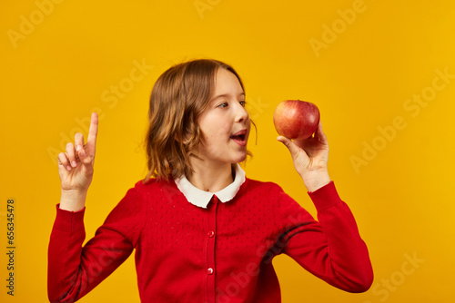 Stylish smiling school teenage girl holding appleson her head photo