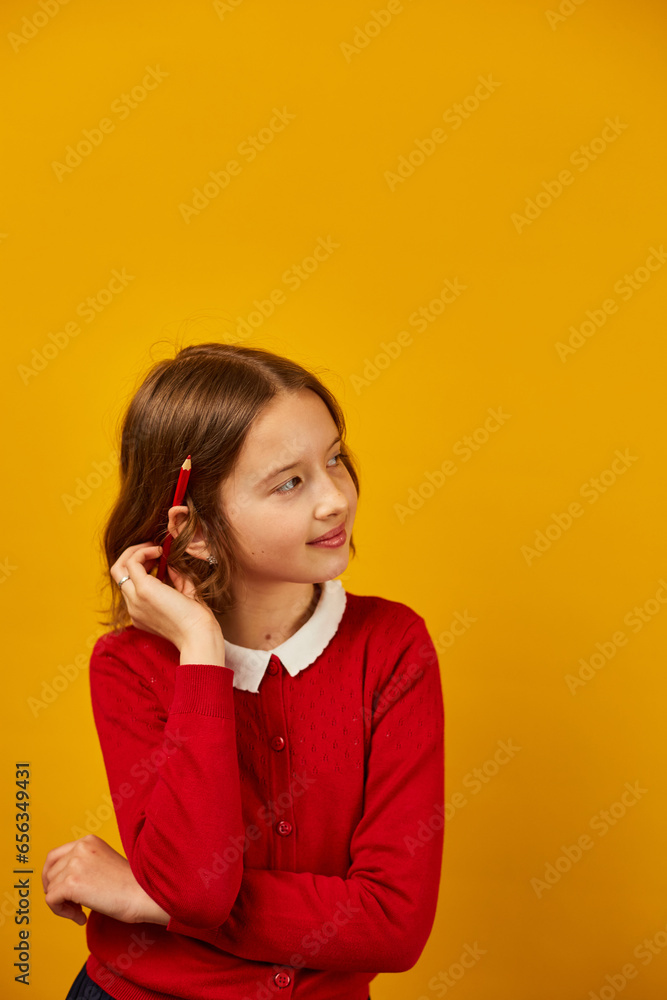 Cute teen school girl is thoughtful with red pencil on her ea Cute teen school girl is thoughtful with red pencil on her ea