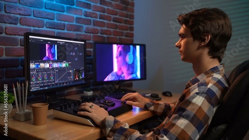Φωτογραφία Portrait of young man in casual at the desk working on pc, looking in monitors, editing video with special equipment