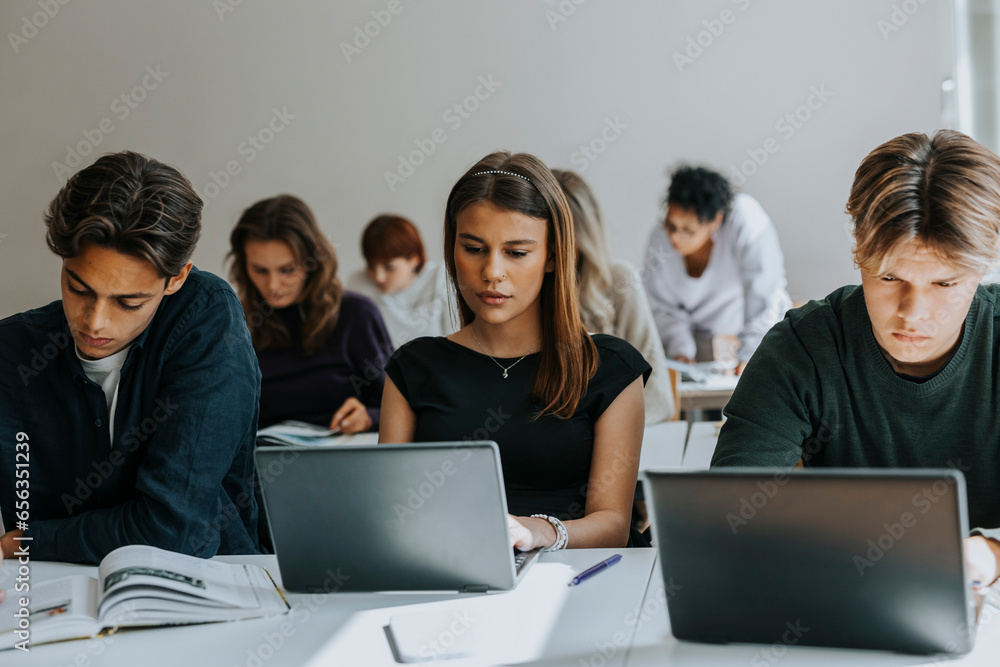 Multiracial teenage students studying at desk in classroom Multiracial teenage students studying at desk in classroom