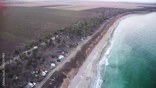 Aerial high angle footage of Camping Ezerets at the Bulgarian black sea coast. Drone flyover top down shot of emerald green water, the surf and camping grounds in Eastern Europe.
 photo