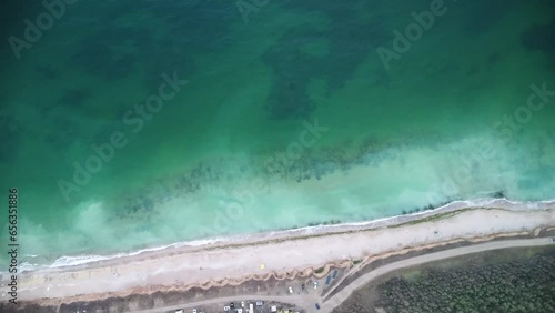 Aerial high angle footage of Camping Ezerets at the Bulgarian black sea coast. Drone flyover top down shot of emerald green water, the surf and camping grounds in Eastern Europe.
 photo