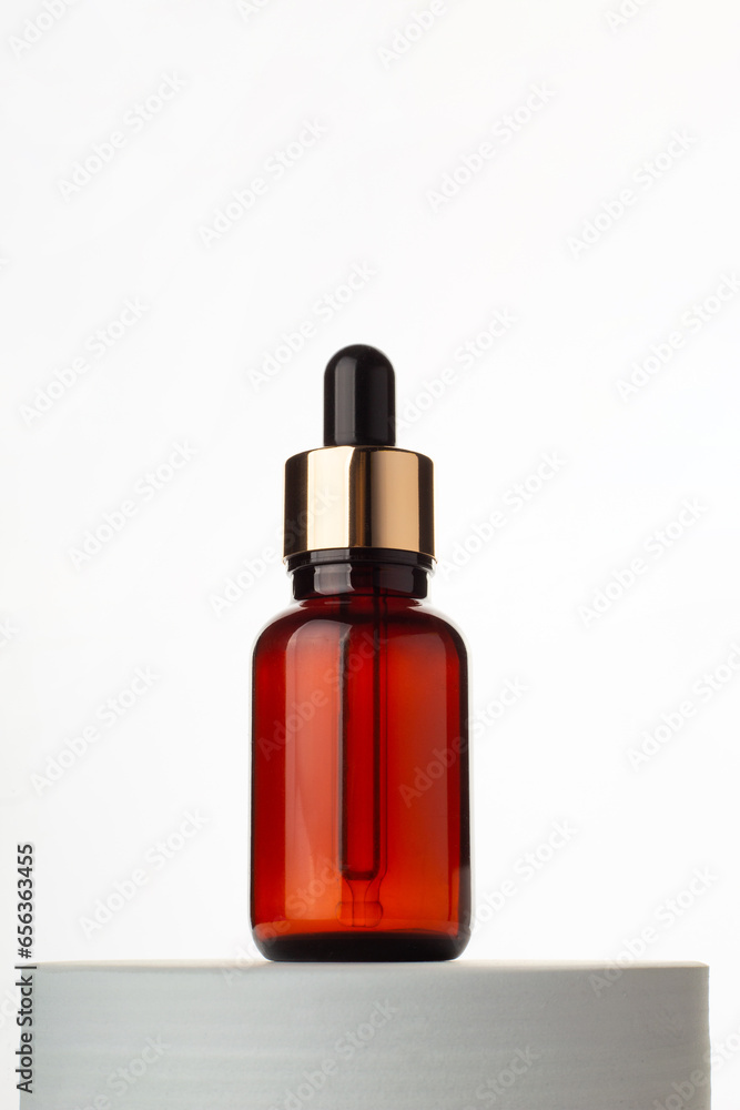 Natural skincare product in glass bottle with dropper. Serum for woman facial skin. Herbal mineral cosmetic, vitamin body oil on white stand. Brown glass bottle cosmetology with pipette. Copy space.