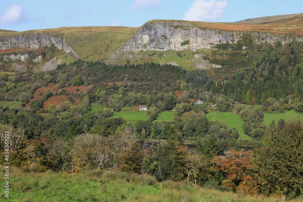 Landscape in autumn at Glencar, County Leitrim, Ireland featuring houses on hillside surrounded by forest  underneath cliff face