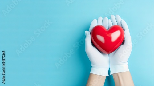 Heart disease prevention - medical gloves holding heart model on light blue background