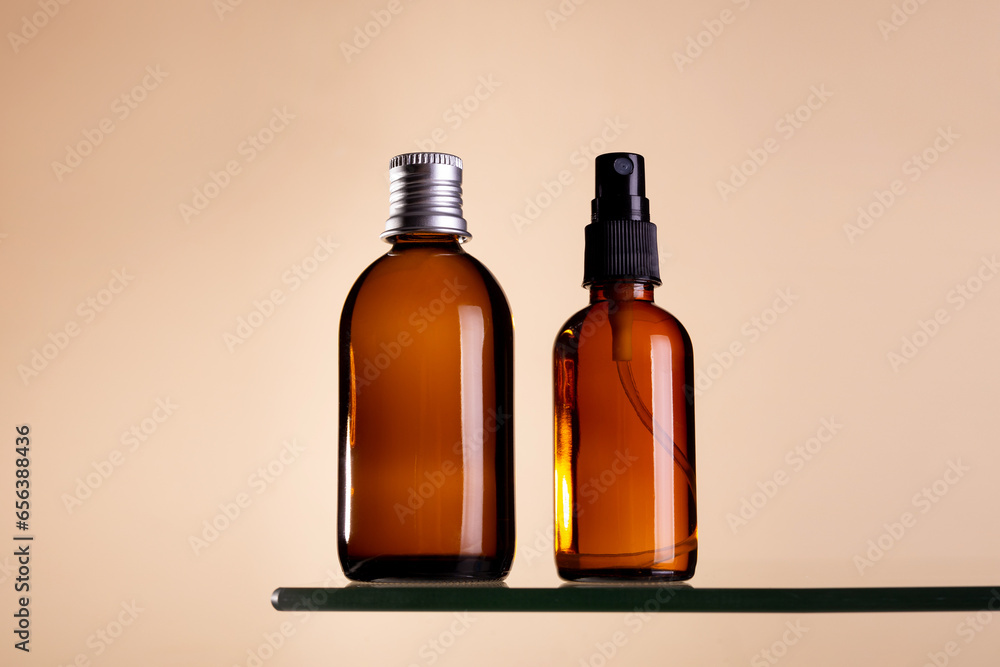 Two cosmetics dark amber glass bottles on beige background. Closeup, copyspace. Beauty blog, salon treatment concept, minimalism brand packaging mock up. Two cosmetics dark amber glass bottles on beige background. Closeup, copyspace. Beauty blog, salon treatment concept, minimalism brand packaging mock up.