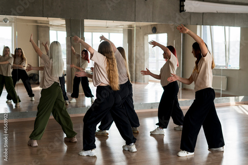 team of young female dancers practice choreography in the studio in front of the mirror
