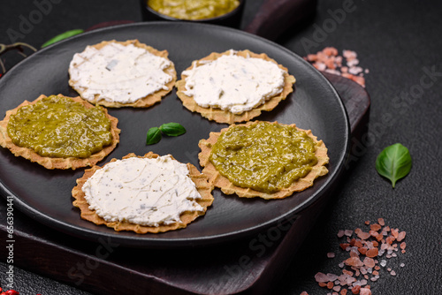 Round snacks with crispy chips or crackers with cream cheese and pesto