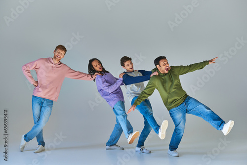 four young cheerful men in casual clothing having fun, hands on shoulders, cultural diversity photo