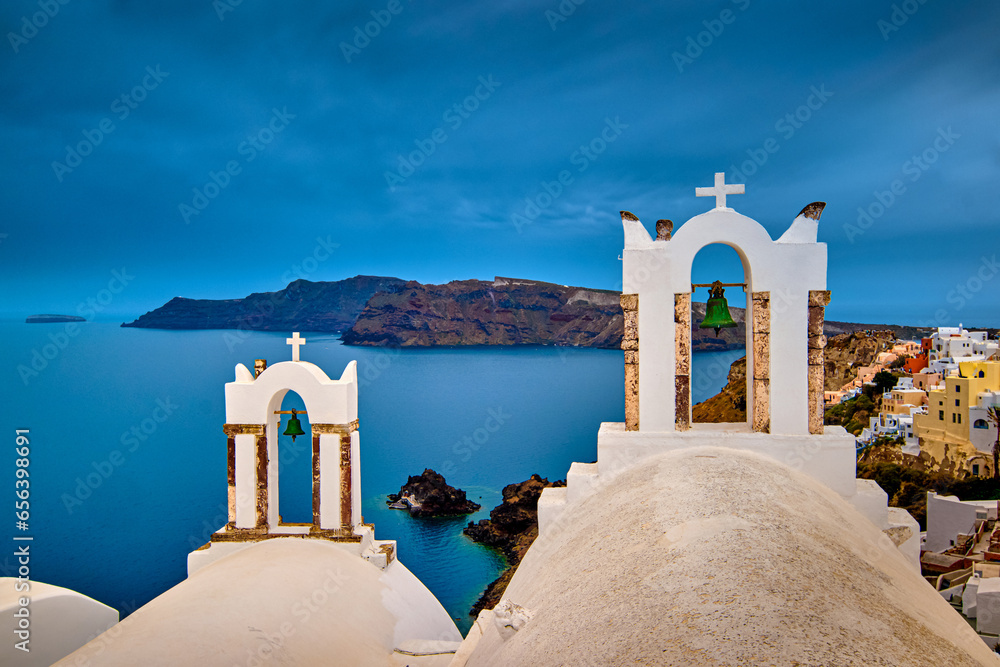 Two bell towers of church in Oia, Santorini island, Greece, seascape.