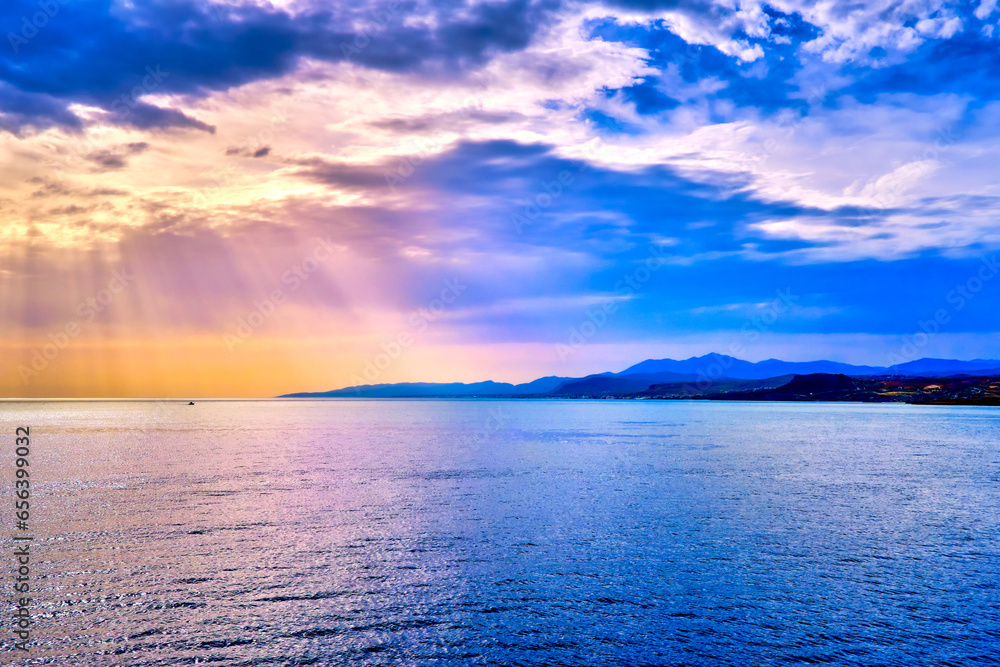 Colorful seascape with clouds and sun rays cast over sea waters