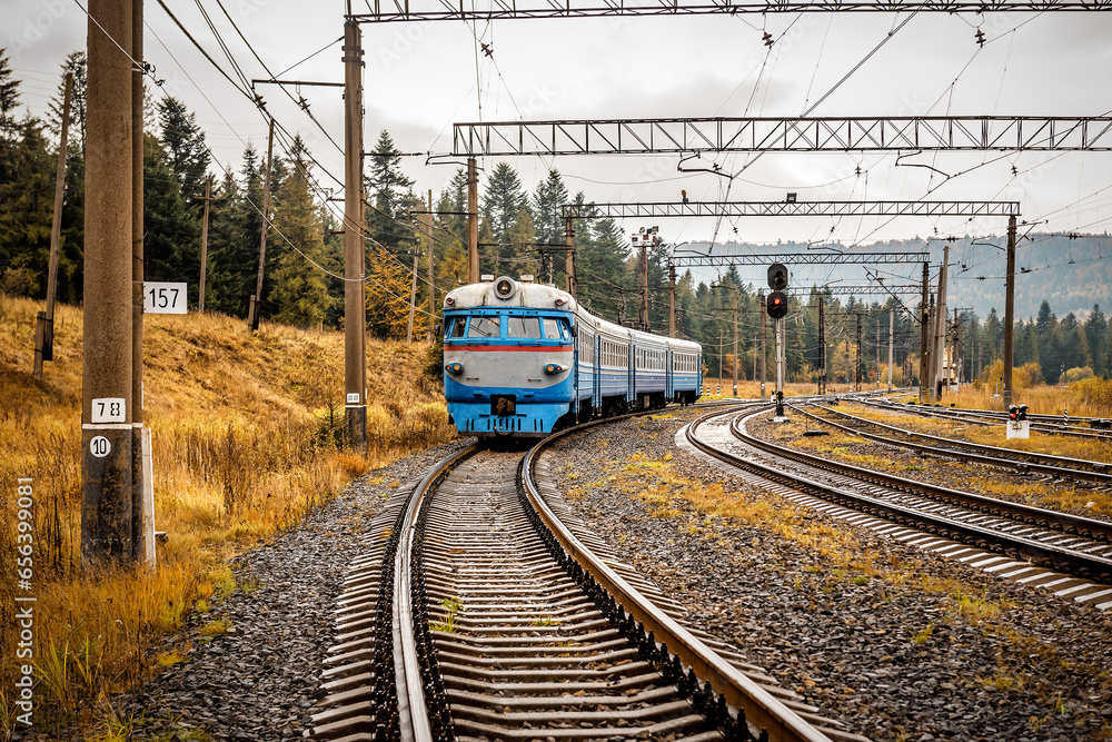 Fototapeta premium An old passenger train rides through autumn mountains