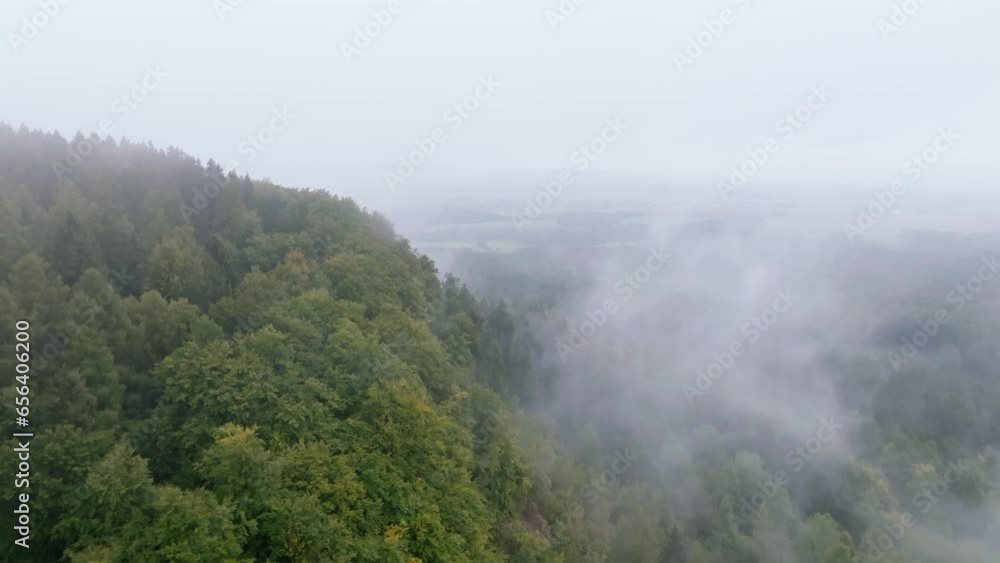 Steep hill covered with green trees in the fog. Autumn cold morning aerial view from drone Steep hill covered with green trees in the fog. Autumn cold morning aerial view from drone