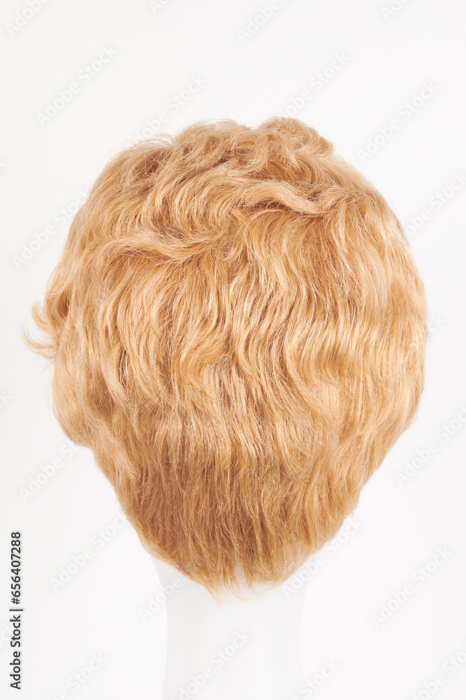 Fototapeta premium Natural looking blonde fair wig on white mannequin head. Short hair cut on the plastic wig holder isolated on white background, back view.