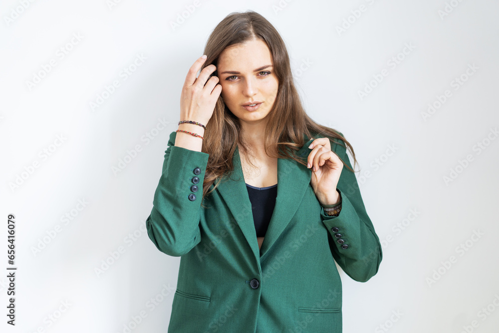 A beautiful girl in a green office-style jacket stands on a white background